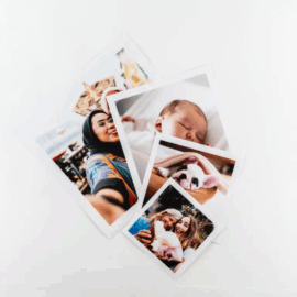 Several printed photos laid on a white background, featuring people, a baby, and a puppy.